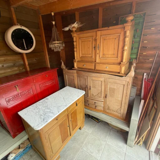 Houten meubels in een schuurtje, een rode kast en een marmeren tafelblad, rustieke stijl en warme tinten zichtbaar.