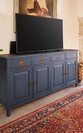 Blauw houten dressoir met tv erop, omgeven door een oosters tapijt en schilderij, klassiek en stijlvol interieur.