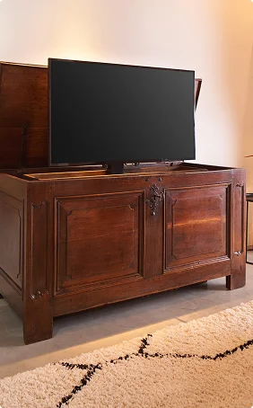 Houten kast met opklapmechanisme voor tv in modern interieur, warme tinten en licht tapijt voor een sfeervol geheel.