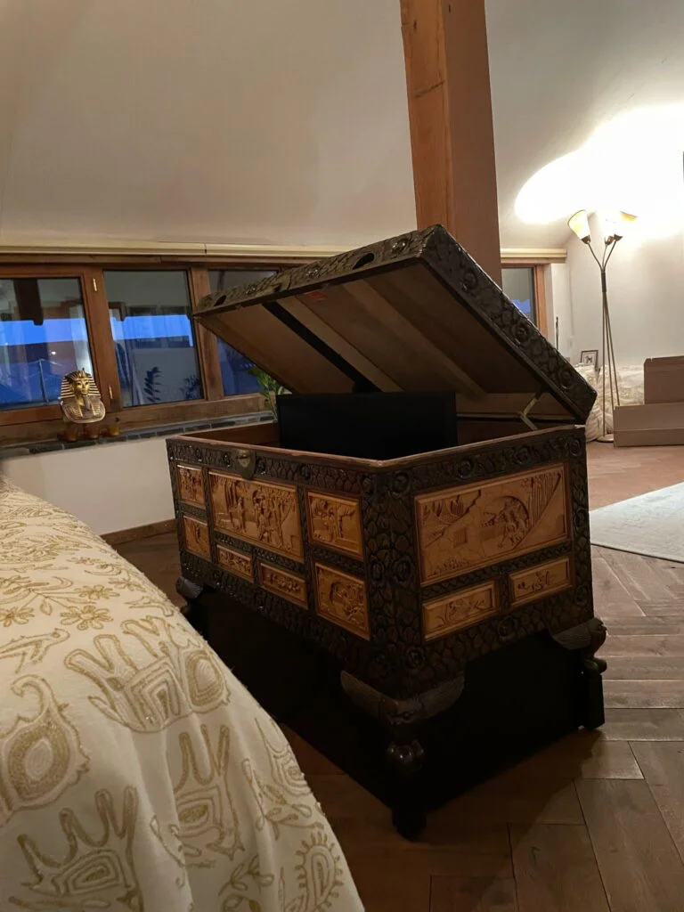 Houten kist met gedetailleerde houtsnijwerk in een warme slaapkamer, functioneert als decoratief TV lift meubel.