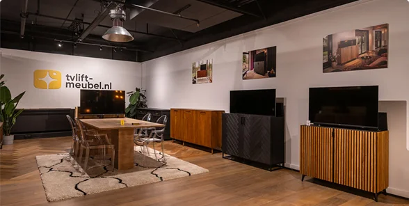 Moderne showroom met stijlvolle TV-meubels van hout en zwart materiaal, naast een houten tafel en transparante stoelen.